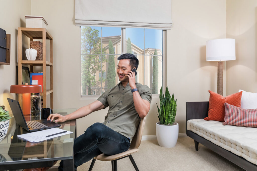 Resident working on his laptop and talking on the phone in his apartment home
