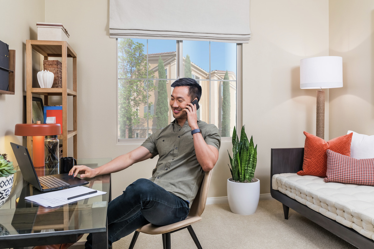 Resident working on his laptop and talking on the phone in his apartment home