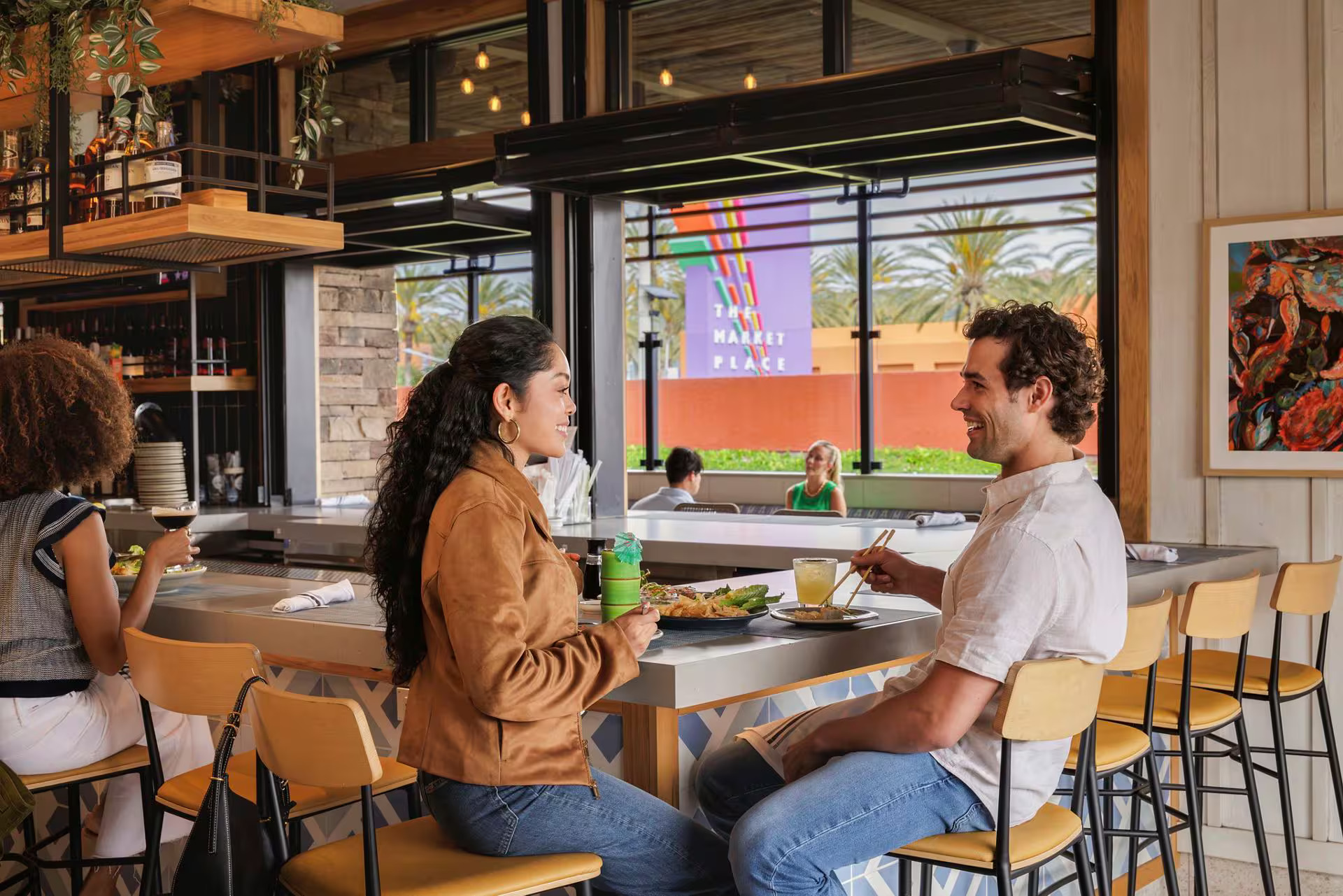 Best Restaurants in Irvine: Man and woman sitting at restaurant with The Market Place signage behind them.