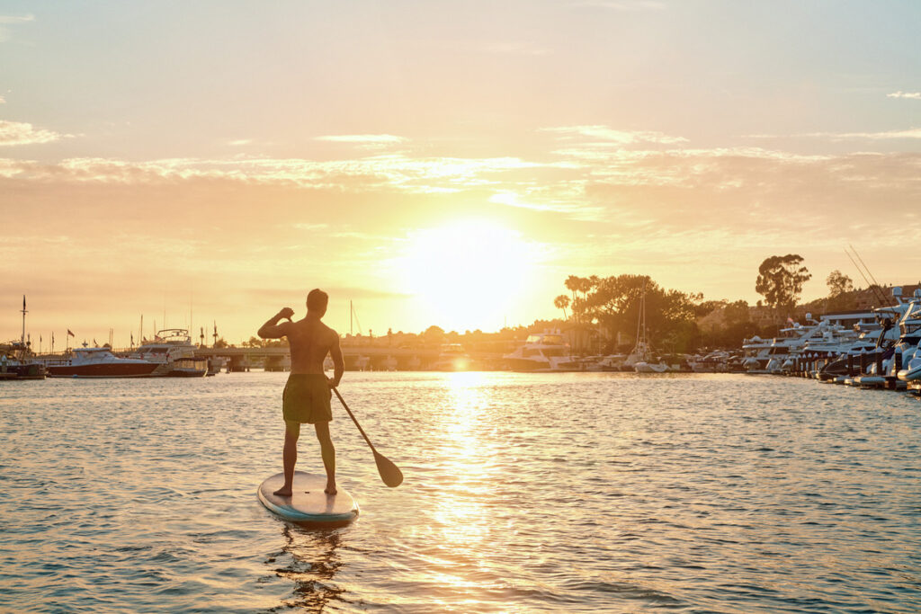 Man paddles boards at sunset near Newport Beach Marina